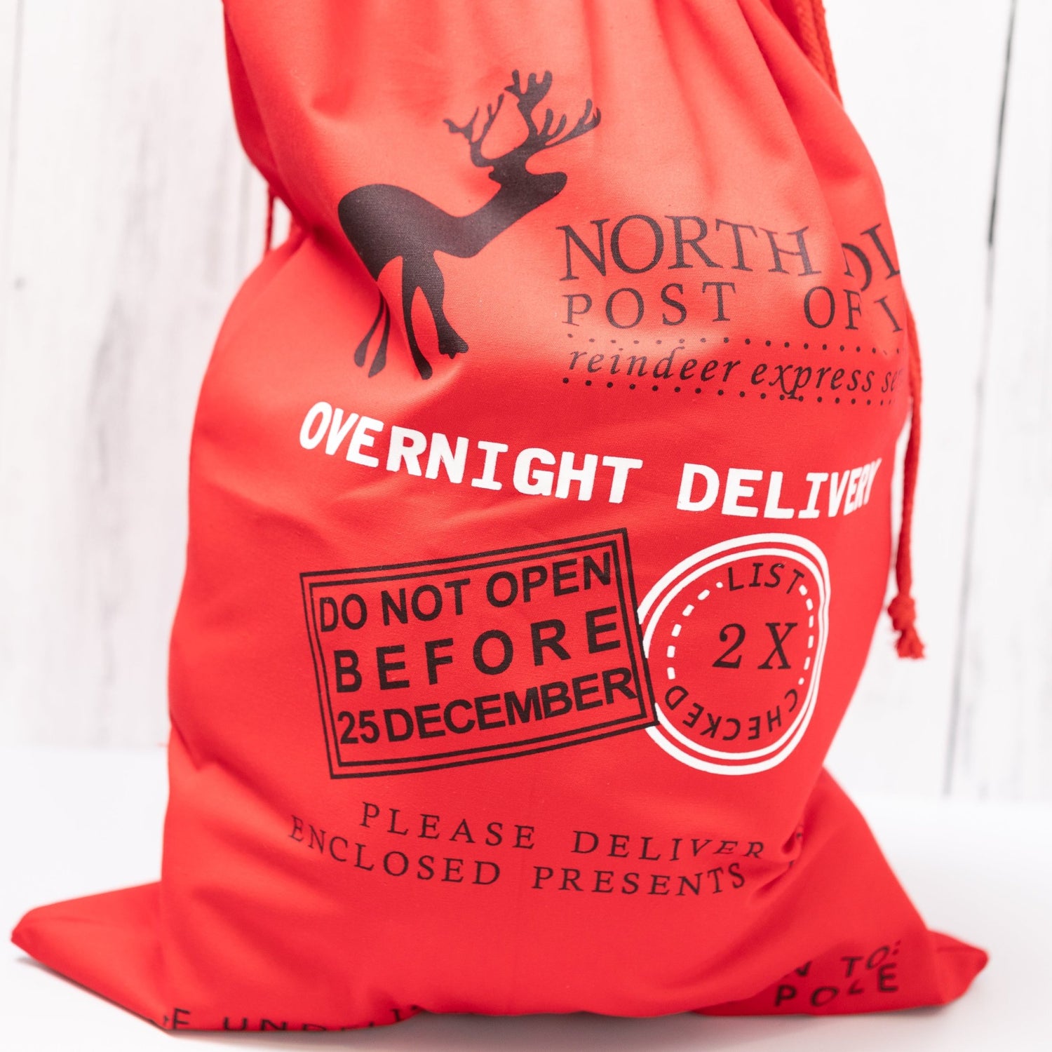 Christmas Gift Bags | Reusable Oversized Fabric with Drawstring Cord - North Pole Post Office Overnight Delivery Logo - Alicia GonzalezGift Bags