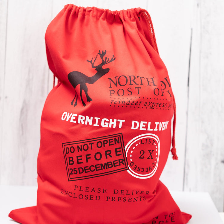 Christmas Gift Bags | Reusable Oversized Fabric with Drawstring Cord - North Pole Post Office Overnight Delivery Logo - Alicia GonzalezGift Bags